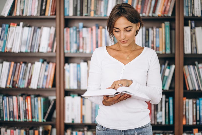 mujer consultando un libro en una biblioteca